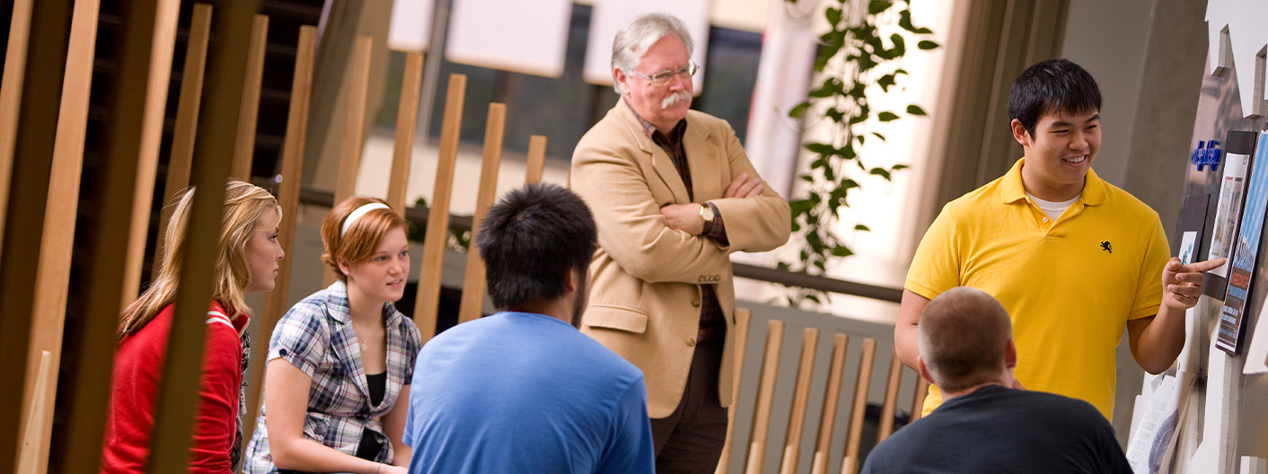 Group of students giving a critique with a faculty member.