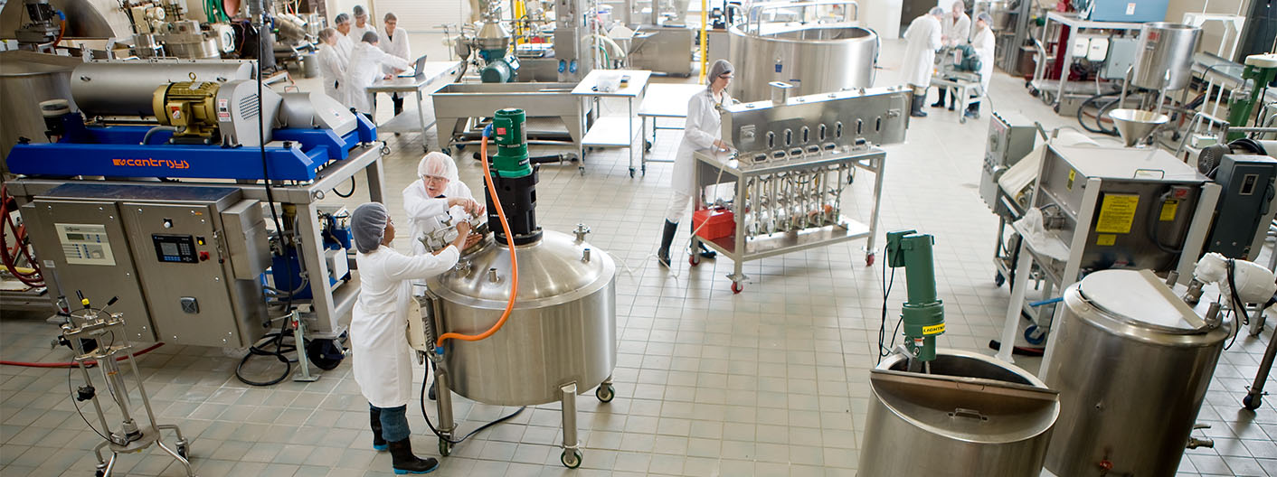 Students and faculty working in a stainless steel food laboratory.