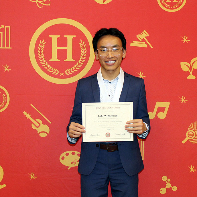 Luke Westrick holding up his honors certificate and medal. 